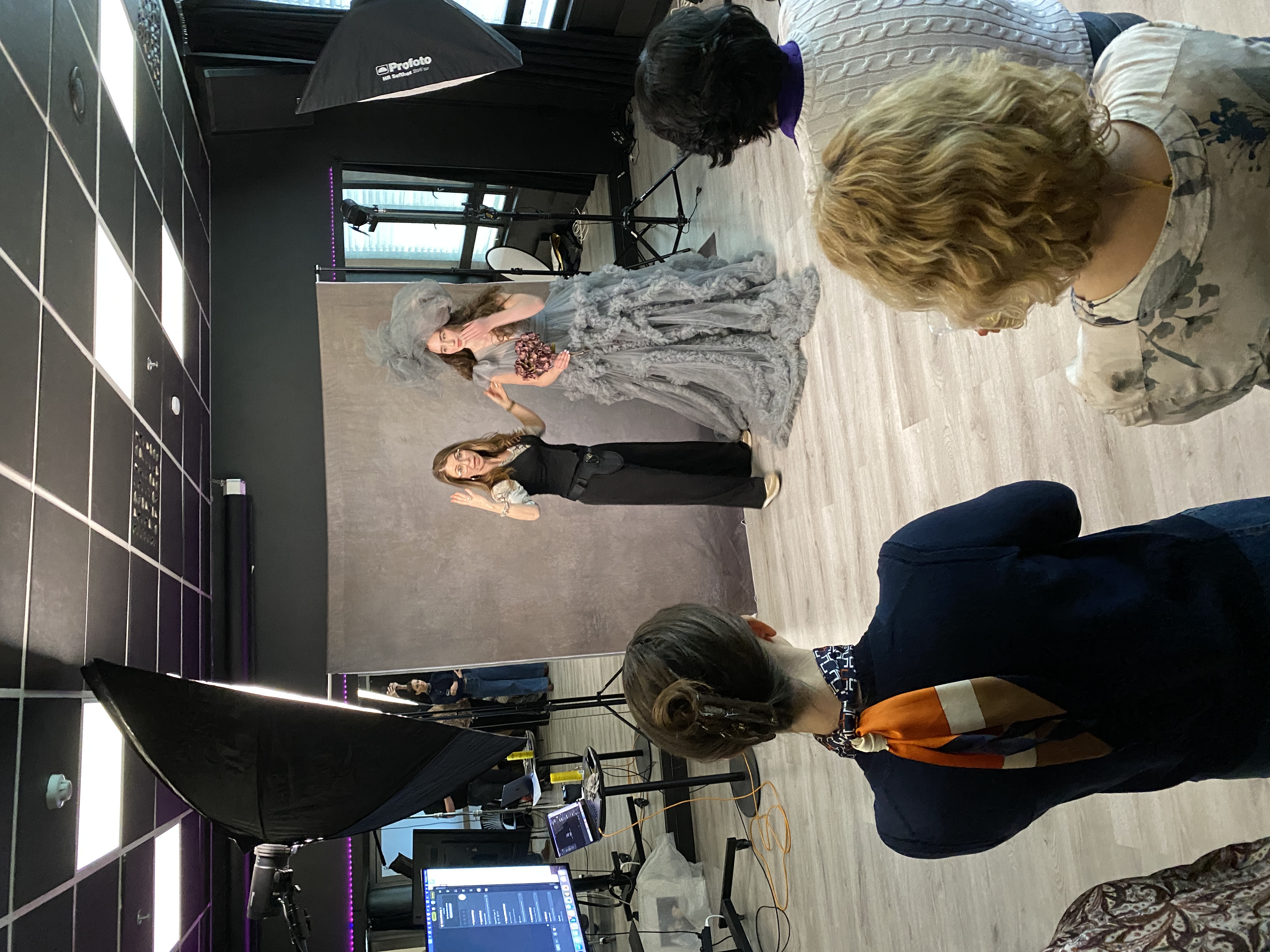 Martina directing a model in a grey ruffled gown, with workshop attendees watching